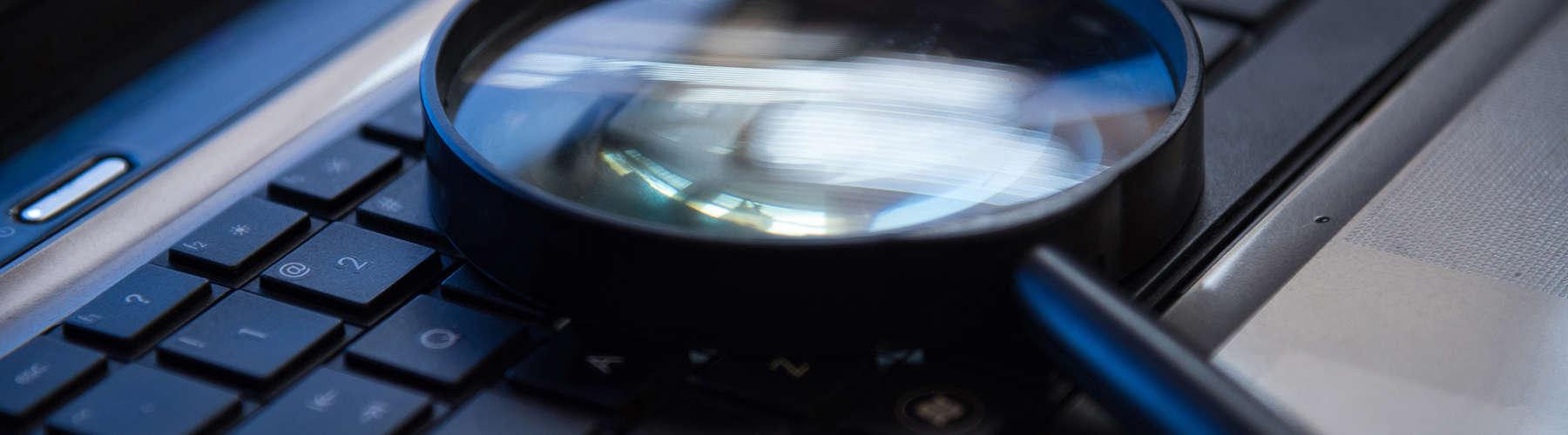 photo of a magnifying glass sitting on a computer keyboard